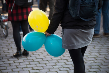 Colmar - France - 5 March 2022 - Closeup of woman with blue and yellow balloons to protest against...