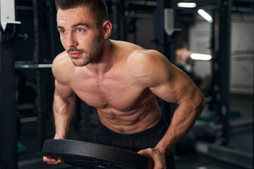 Fototapeta na wymiar Focused photo on brunette man lifting weights