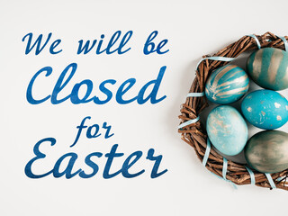 Signboard with the inscription We will be closed for Easter. Easter eggs painted with colorful paints. Closeup, indoors, no people. Congratulations for loved ones, relatives, friends, colleagues