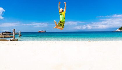 Relaxation and fun of a summer holiday in freeday with young man jumping on beach in summer tropical  background