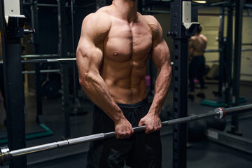 Focused photo on strong sportsman lifting barbell