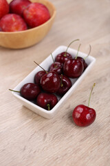 Fresh cherry in white dish on wooden background