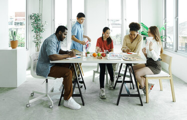 African American male teacher sitting at table with pupils teaching drawing lesson in modern classroom. Group of diverse children sit together having fun being artist drawing activity and painting.