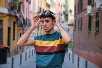 Fototapeta premium Young caucasian man with long false nails posing with his sunglasses looking at camera at street.