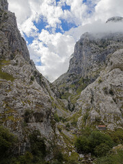 Fototapeta premium Paisaje de alta montaña con nubes y picos en la ruta del Cares desde Poncebos en Asturias, para senderistas amantes de la naturaleza y excursiones de montaña, en el verano de 2020