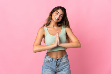Young caucasian woman isolated on pink background keeps palm together. Person asks for something