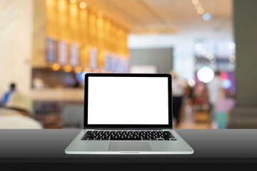 Laptop, computer notebook  with blank screen on black table with blurred background in the cafe, warm light tone.