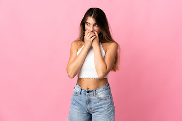 Young caucasian woman isolated on pink background covering mouth and looking to the side