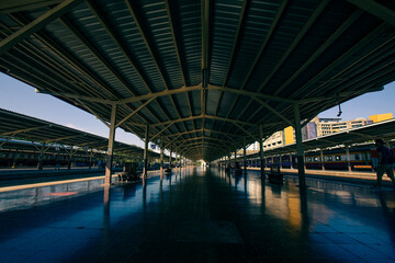 Perspective railway station platform under a steel frame roof