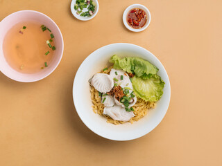 Fototapeta na wymiar vietnamese food Sliced Fish Noodle in a bowl with soup, chili sauce and spring onion top view on wooden table