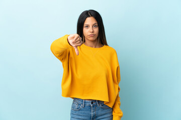 Caucasian girl isolated on blue background showing thumb down with negative expression