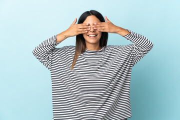 Caucasian girl isolated on blue background covering eyes by hands and smiling