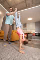 Male holds a legs of girl while doing a handstand