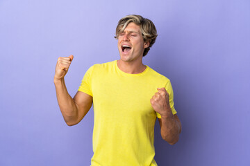 English man over isolated purple background celebrating a victory