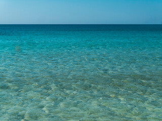 Smooth sea waves blue pattern under crystal clear light blue sky