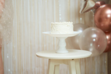 White birthday cake with balloons on the background