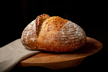 Sourdough bread on linen cloth on brown chopping board.