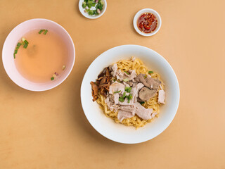 Minced meat Noodle in a bowl with soup, chili sauce and spring onion top view on wooden table