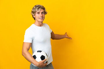 English football player over isolated yellow background extending hands to the side for inviting to come