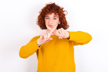 young redhead girl wearing yellow sweater over white background has rejection angry expression...