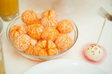 Delicious peeled tangerine slices lie in a transparent plate with desserts