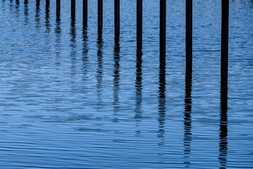 sich auf dem Wasser spiegelnde Pf&auml;hle in einem Hafen