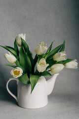 White tulips in white vase on grey and white background 