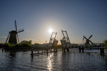 Fototapeta na wymiar Windmills and wooden bridge by the water at Kinderdijk