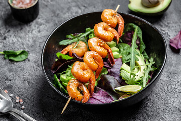 Vegetarian vegetable low carb lunch bowl with avocado, fresh salad, grilled shrimps and pesto sauce. Healthy diet seafood concept. Top view