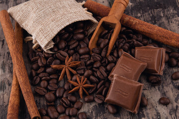 chocolate, cinnamon sticks  and coffee beans on wooden background