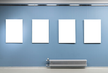 Four blank white vertical posters hang on blue wall - Powered by Adobe