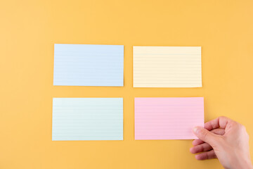 hand putting blank writing paper and three empty papers on a yellow background. space for text.