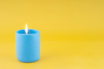 Blue candle on yellow background Space for text