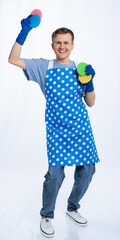a man in a blue apron, rubber gloves, an orange t-shirt, jeans and white sneakers holds sponges for...