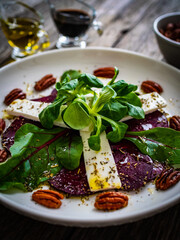 Beetroot carpaccio with goat cheese and pecan nuts  on wooden background
