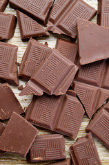 Heap of cracked chocolate bar scattered on wooden background