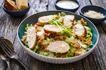 Caesar salad - fried chicken breast and vegetables on wooden table