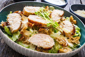 Caesar salad - fried chicken breast and vegetables on wooden table