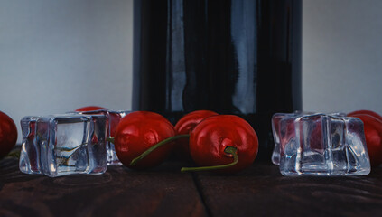Banch of red cherry and ice cubes. A bottle of wine lower angle