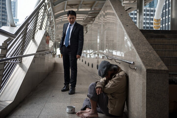 Kind businesman look at homeless man in city