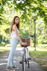 Naklejka premium Asian woman hold bike in spring park in sunny day