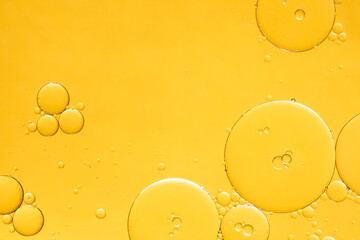 Golden yellow abstract oil bubbles or face serum background. Oil and water bubbles macro...
