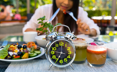 Selective focus of  Alarm  Clock which reminding us to include delicious fresh vegetables as part of a daily modern healthy lifestyle diet