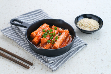 Tteokbokki or Topokki , stir fried rice cake stick, popular Korean street food with spicy gochujang sauce and sesame seed. 
