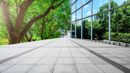 Empty square floor and green tree with glass wall building