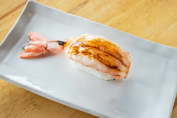 Burnt sweet shrimp topped with spicy sauce and creamy salad nigiri sushi. Selective focus.