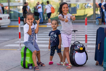 three kids at the airport with  suitcases and bags, multi-ethnic family travelling 