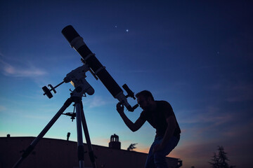 Silhouette of a man and telescope under the starry skies.