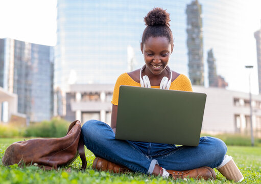 cute afro american woman studying in the park of her city, student preparing outdoor research, concept of internet connection and remote working