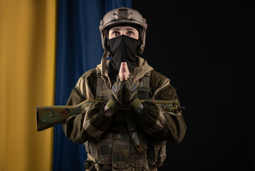 a male soldier in a military uniform and helmet with a weapon on the background of the national...